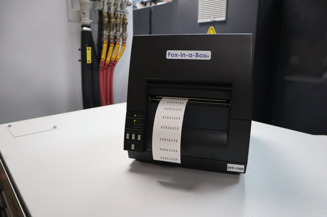 Fox-in-a-Box Thermal Label Printer with Patch Panel Labels coming out of the front, set in an industrial setting